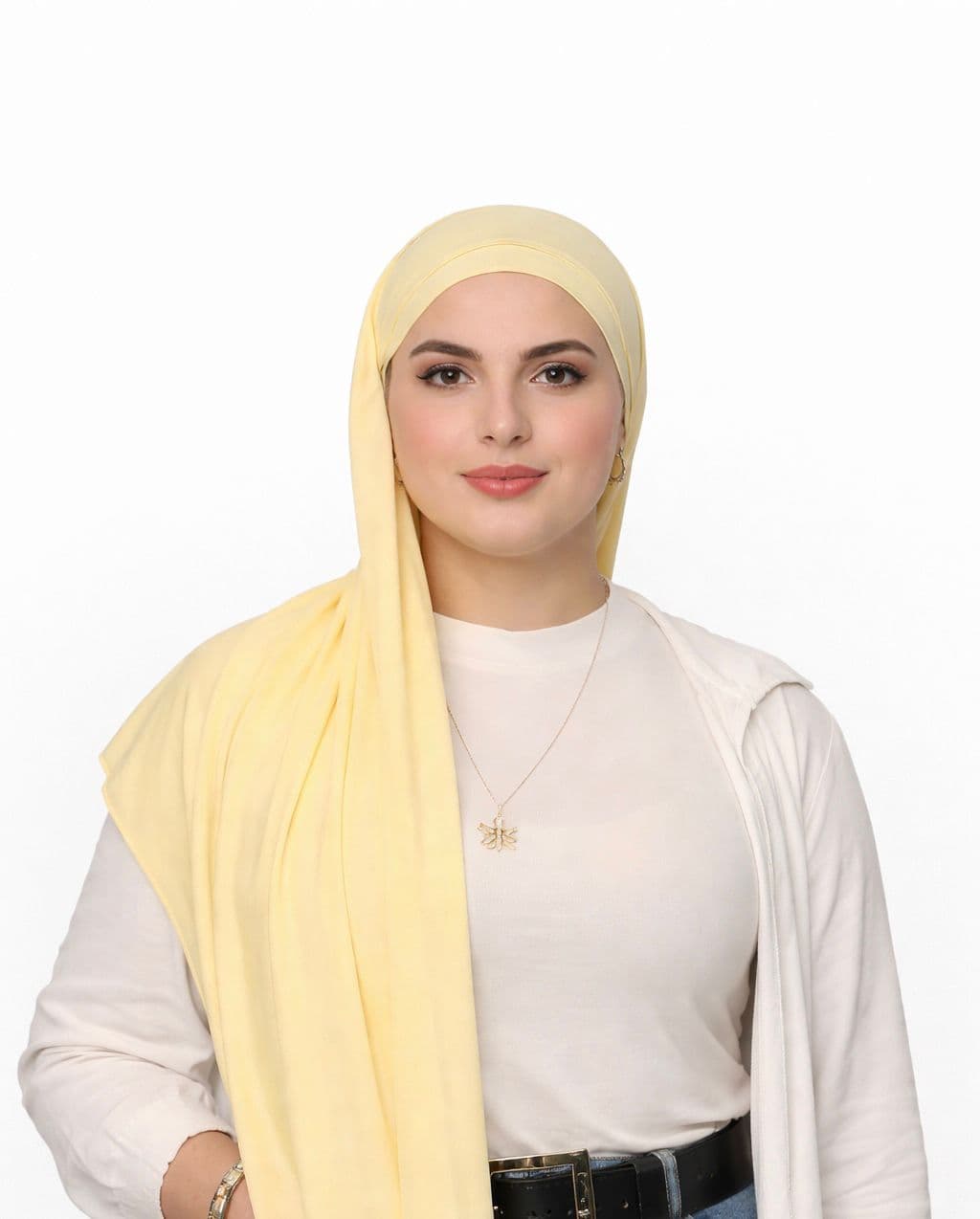 Frau mit hellgelbem Hidschab, weißem Oberteil und goldener Kette blickt freundlich in die Kamera.